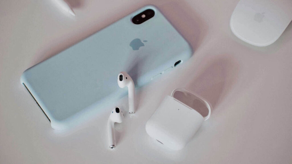 Apple AirPods and charging case beside an iPhone, useful earphones for travel