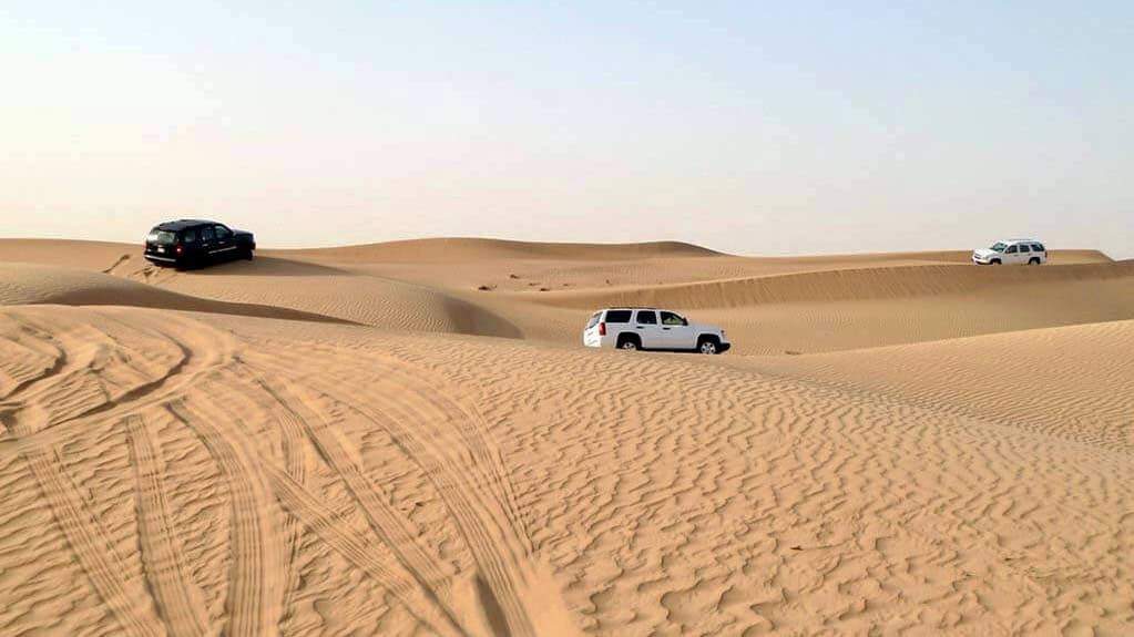 Four-wheel-drive vehicles crossing sand dunes on a Dubai desert safari is a reason to visit Dubai