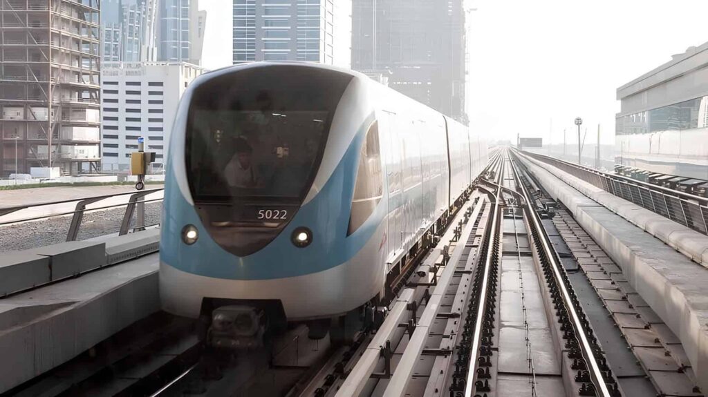 Dubai Metro train travelling on elevated tracks between modern skyscrapers