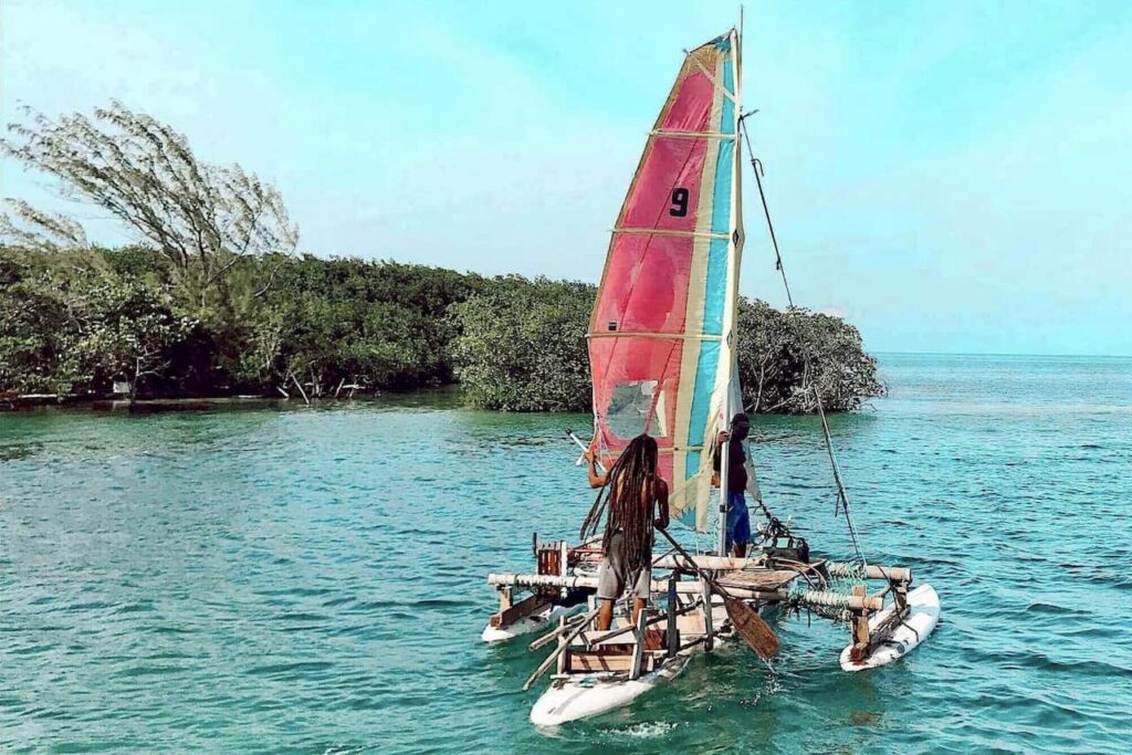 Colorful sailboat navigating turquoise waters near the mangroves of Belize, one of the adventurous places for water activities