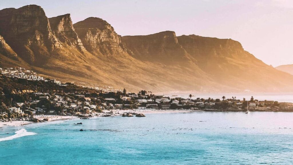 Scenic Cape Town coastline with Table Mountain overlooking turquoise waters and a sandy beach at sunset