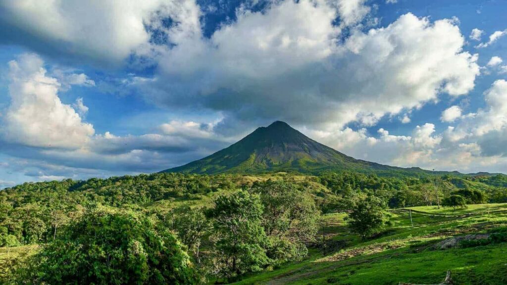 Arenal Volcano rising above the lush green landscape of Costa Rica under a dramatic blue sky