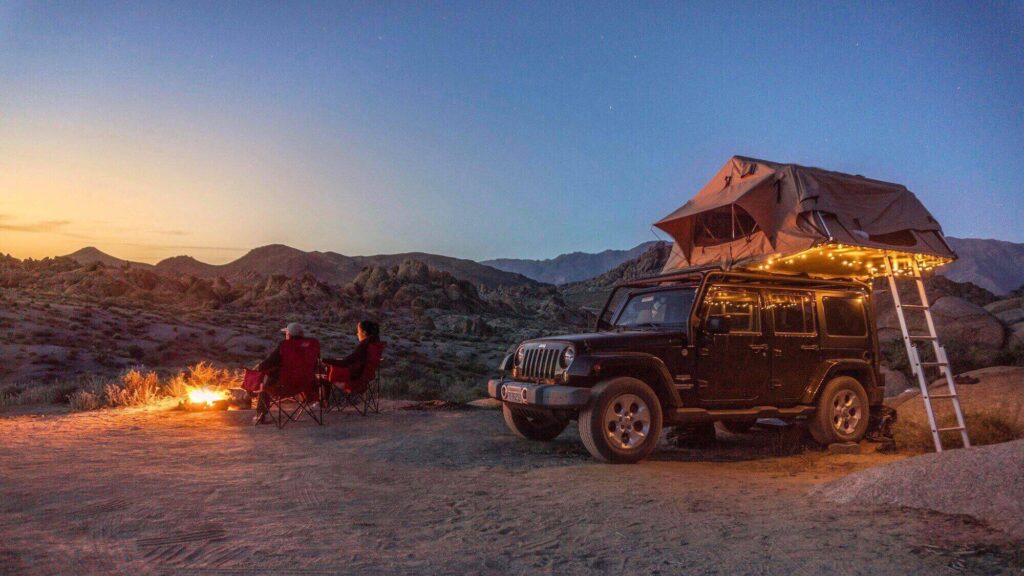 Camping on top of a jeep with backpacking gear