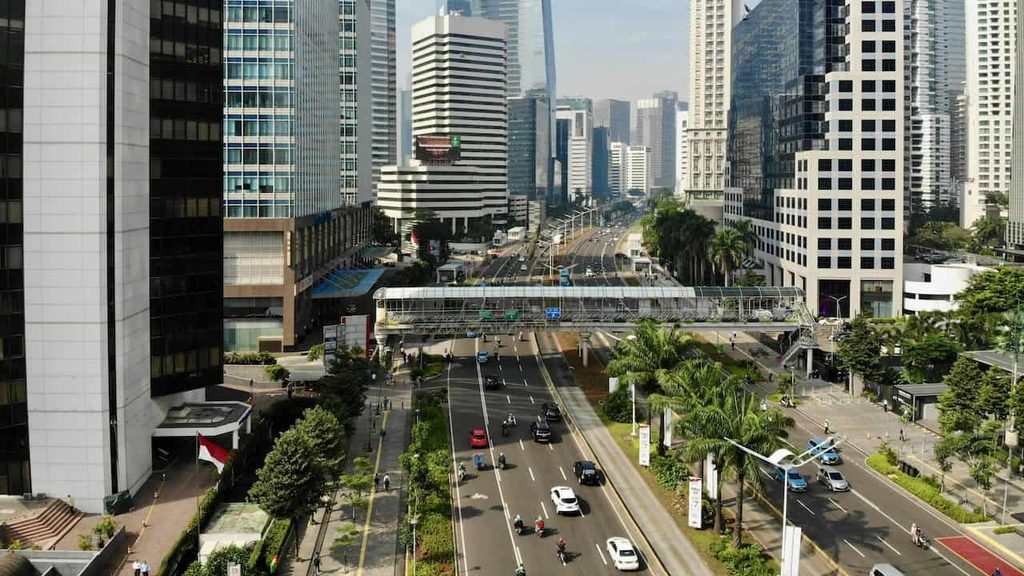 Jakarta city center skyline with modern skyscrapers, busy roads, and a pedestrian bridge