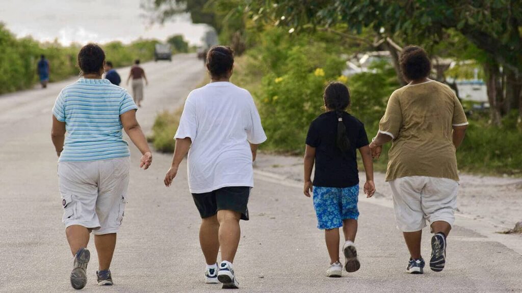 Four people walking along a road in Nauru