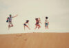 a family of 5 jumping on a sand dune in summer vacation