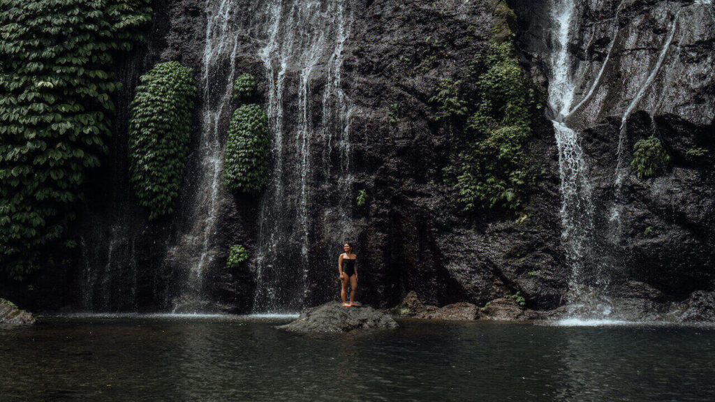 a girl under a Bali's waterfall