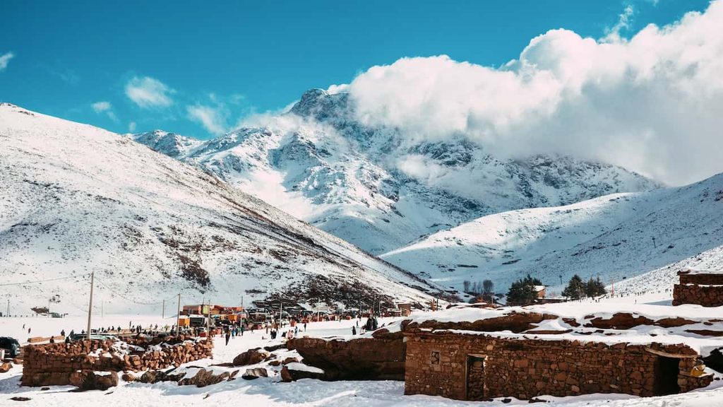 Snow-covered Oukaïmeden mountains and traditional stone buildings in Morocco