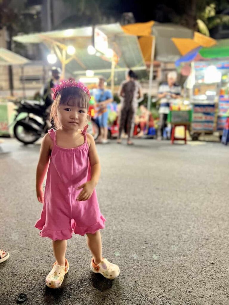 a little girl is strolling in Ninh Kieu night market