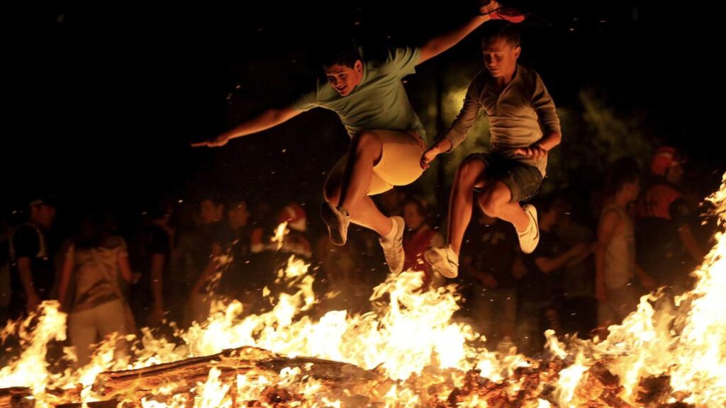 two men jump over the bonfire at La Noche de San Juan festival in Spain