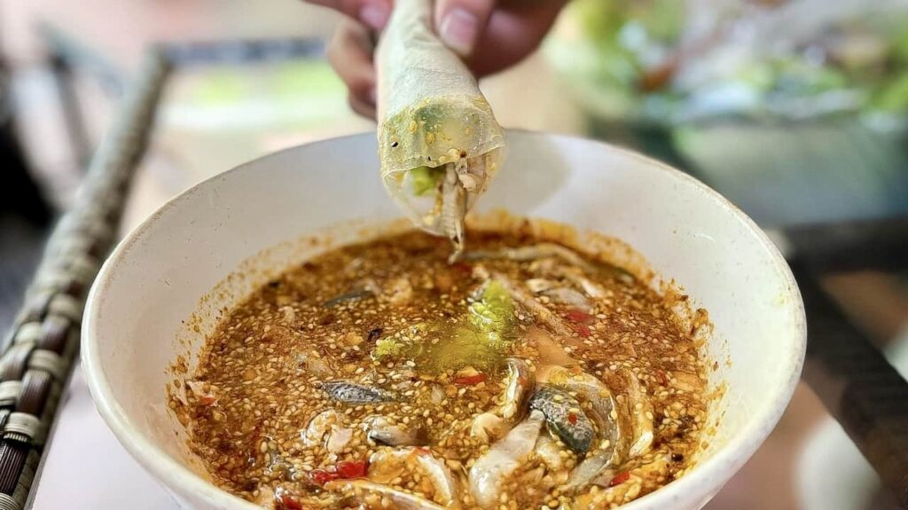 Nam O fish rolls dipping into Nam O fish sauce