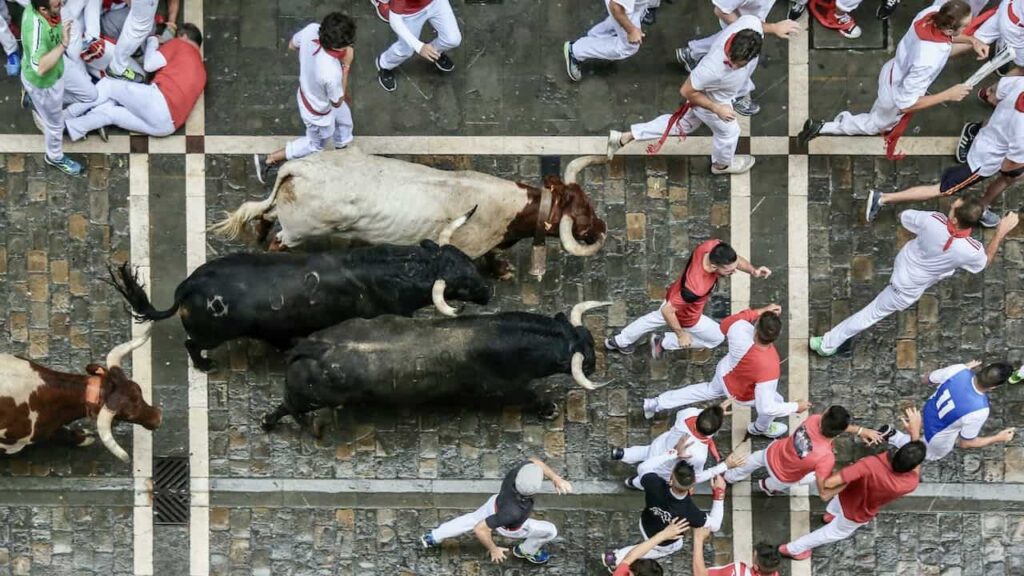 people are running from the bulls at the San Fermín festival in Pamplona Spain