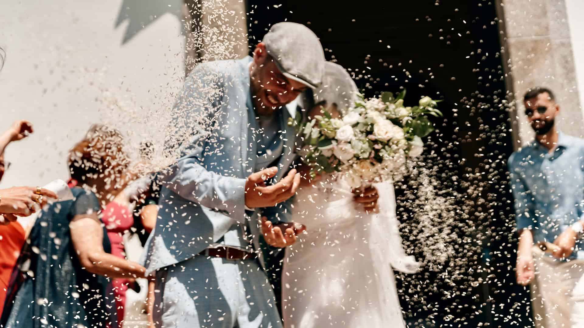 Guests throwing rice over a newlywed couple during a wedding ceremony, symbolizing cultural wedding traditions and celebration