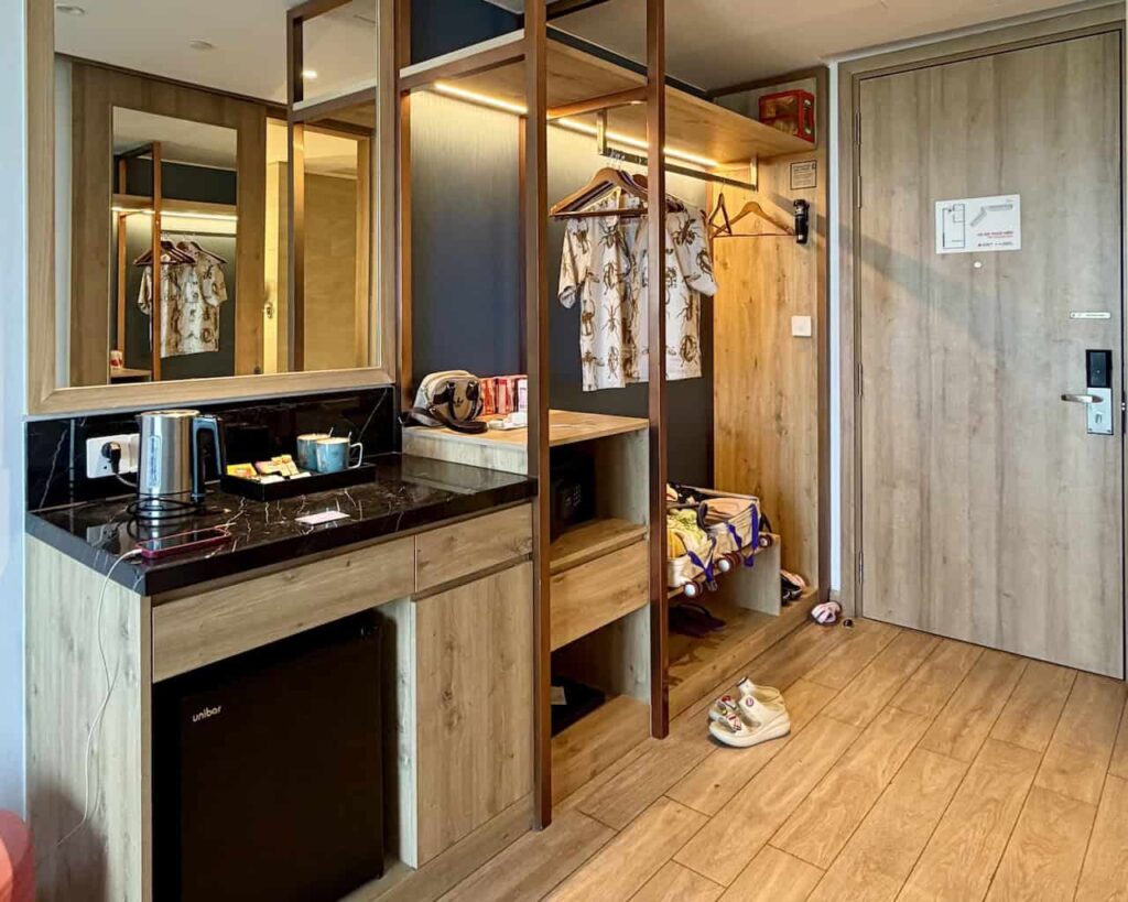 Entrance area with minibar and open wardrobe inside the Classic Sea View King room at Dhawa Ho Tram.