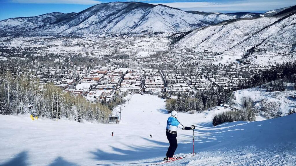 Skier enjoying a snowy slope overlooking Aspen, Colorado, in winter