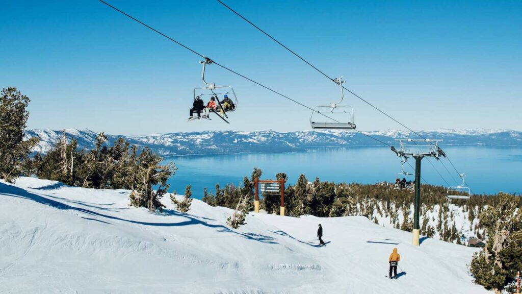 Skiers on a snowy Lake Tahoe slope with the lake and mountains in the background